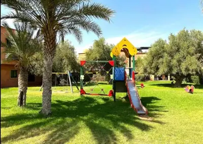 a playground in a park with a palm tree at Dar Celya Sfia in Marrakech
