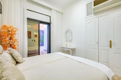 a white bedroom with a large white bed and a door at Villa YOGA Guéliz Centre-Ville in Marrakech