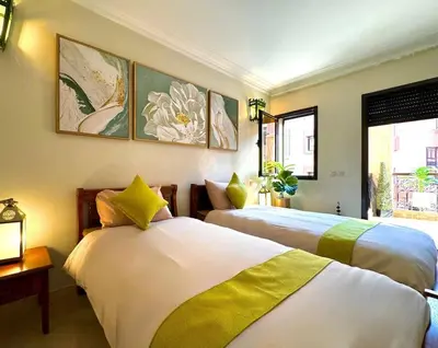 two beds in a room with paintings on the wall at Piscine Guéliz Center Yoga in Marrakech