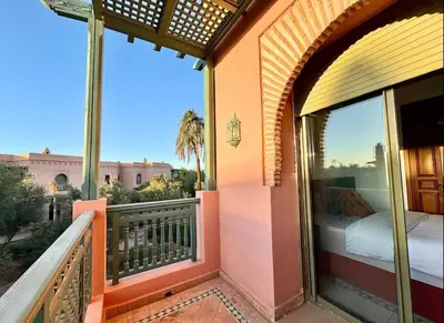 a balcony with a bed and a view of a building at Paradis à marrakech Grande Piscine in Marrakech