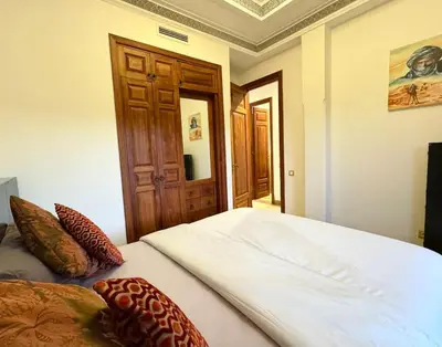 a bedroom with a large white bed and a wooden door at Paradis à marrakech Grande Piscine in Marrakech