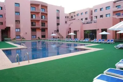a large hotel with a large swimming pool with chairs and umbrellas at Tulipe Family House-Pool and Parking in Marrakech