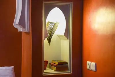 a mirror in a room with some books at Appartement Riad élégant chic au cœur de Guéliz in Marrakech