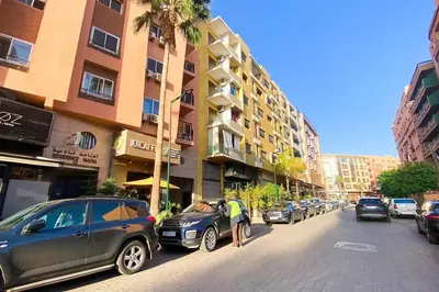 a man standing next to cars parked on a city street at Appartement Riad élégant chic au cœur de Guéliz in Marrakech