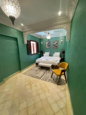 a green room with a bed and a table and chairs at Riad Naffar in Marrakech