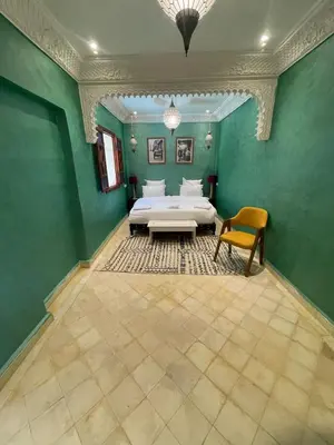 a bedroom with a bed and a table and a chair at Riad Naffar in Marrakech