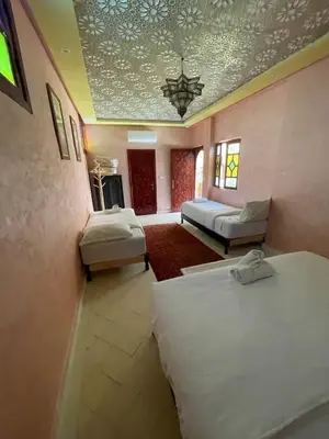 a bedroom with two beds and a living room at Riad Naffar in Marrakech