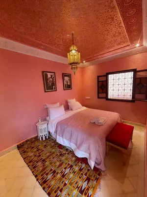 a bedroom with a large bed and a chandelier at Riad Naffar in Marrakech