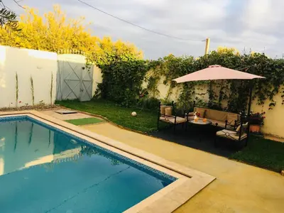 a swimming pool with a table and an umbrella at Dari in Marrakech