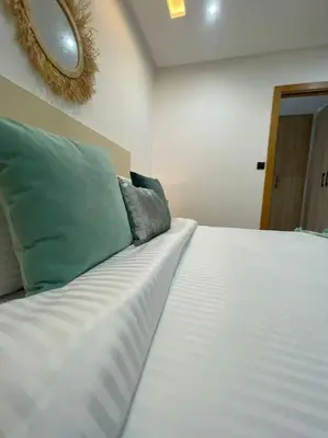 a white bed with green pillows in a room at La Bohéme - Duplex Neuf - Modern & Chic - Proche Gare - Confort - CLIM Parking et WIFI Gratuit ! GUELIZ in Marrakech