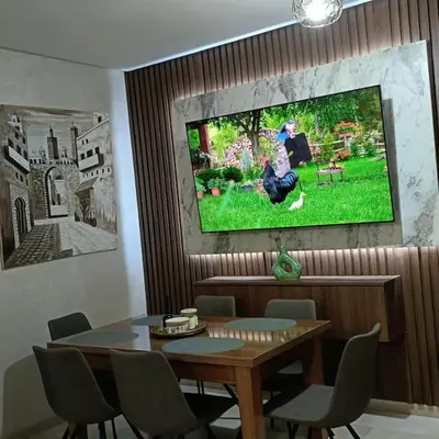 a dining room with a table and a tv on the wall at superbe appartement à côté de la gare à Gueliz Marrakech in Marrakech
