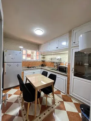 a kitchen with a wooden table and black chairs at Cozy Apartment near airport in Marrakech