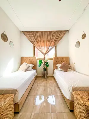 two beds in a room with a window at Élégant appart 3 chambres cozy avec piscine in Marrakech