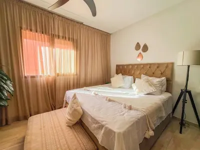 a bedroom with a large bed and a window at Élégant appart 3 chambres cozy avec piscine in Marrakech
