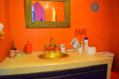 an orange bathroom with a sink and a mirror at Riad les ANGES DU DESERT in Marrakech