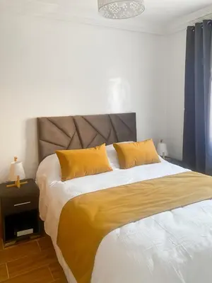 a bedroom with a large bed with yellow pillows at Appart Cosy in Marrakech