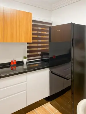 a kitchen with a black refrigerator and white cabinets at Appart Cosy in Marrakech
