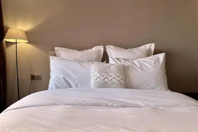 a white bed with white pillows and a pillow on it at Apartment in the heart of Marrakech in Marrakech