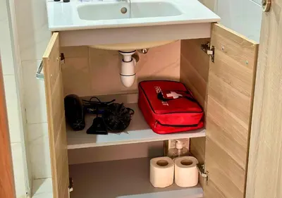a bathroom cabinet with a sink and a red bag at Reflet du Désert Appartement bohème à Marrakech in Marrakech
