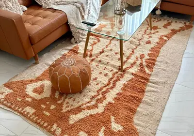 a living room with a glass table and an orange rug at Reflet du Désert Appartement bohème à Marrakech in Marrakech