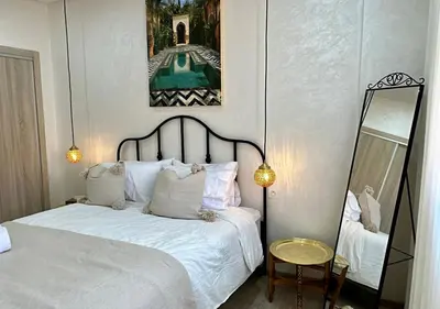 a bedroom with a white bed and a mirror at Trésor andalous in Marrakech