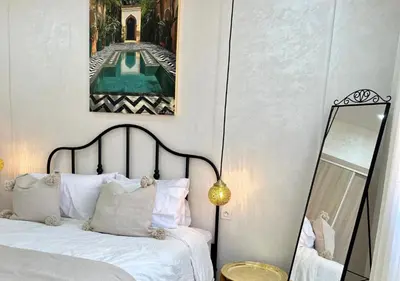 a bedroom with a bed with a mirror and a painting at Trésor andalous in Marrakech