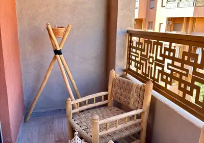 a wooden tripod next to a chair on a balcony at Trésor andalous in Marrakech