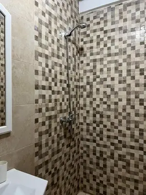 a bathroom with a shower with a tiled wall at Cozy Nour in Marrakech