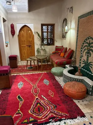 a living room with a red rug and a couch at Riad Dutilleul in Marrakech