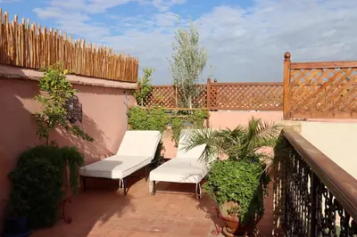 a patio with two white chairs and a fence at Riad Dutilleul in Marrakech