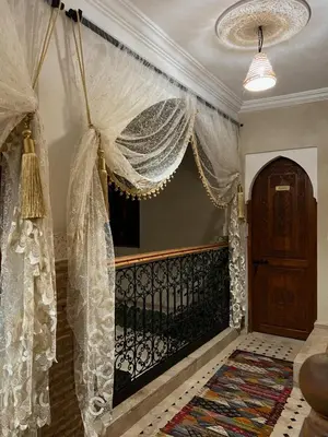 a room with a balcony with curtains and a door at Riad Dutilleul in Marrakech