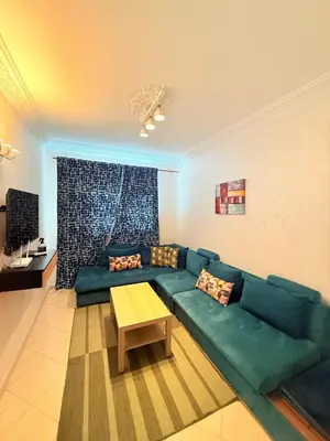 a living room with a green couch and a table at Appart FAMILY lumineux & terrasse privé in Marrakech
