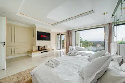 a white bedroom with two beds and a tv at White Mansion in Tameslouht