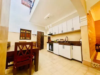 a large kitchen with white cabinets and a wooden table at Dar Rahma- old Town Marrakech in Marrakech