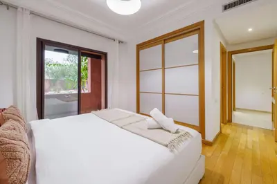 a bedroom with a white bed and a window at Appartement de charme residence avec piscine WiFi in Marrakech
