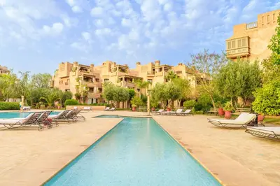 a swimming pool with lounge chairs and a building at Appartement de charme residence avec piscine WiFi in Marrakech