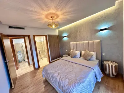 a bedroom with a large bed and a chandelier at Pearl Garden Appart 2 chambres Luxe Cosy Moderne in Marrakech