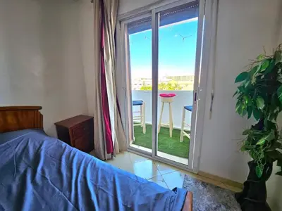 a bedroom with a bed and a door to a balcony at Reda appartement in Marrakech