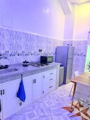 a kitchen with white cabinets and a sink and a refrigerator at Appart Cosy Près de laéroport Adapté au Famille in Marrakech