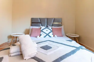 a bedroom with a large bed with pink and blue pillows at Appartement à Marrakech in Marrakech