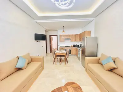 a living room with two couches and a table and a kitchen at New Apartment in Guéliz, Pool, Balcony & Parking in Marrakech