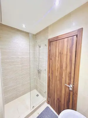 a bathroom with a shower with a wooden door at New Apartment in Guéliz, Pool, Balcony & Parking in Marrakech
