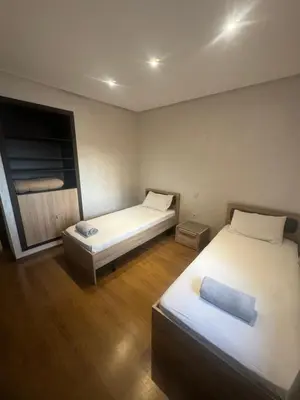 two beds in a small room with wooden floors at Cosy-Appart in Marrakech