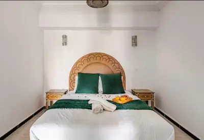 a bedroom with a large bed with green pillows at Appart hôtel avec piscine in Marrakech