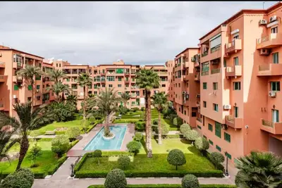 an apartment complex with a swimming pool and palm trees at Appart hôtel avec piscine in Marrakech