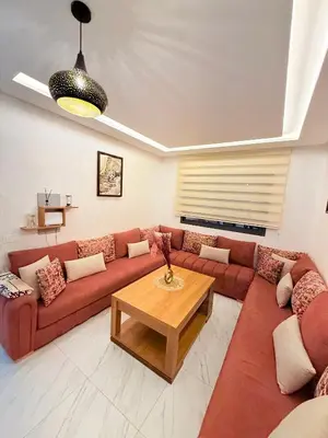 a living room with a red couch and a table at STUDIO luxueux COSY FAMILY in Marrakech