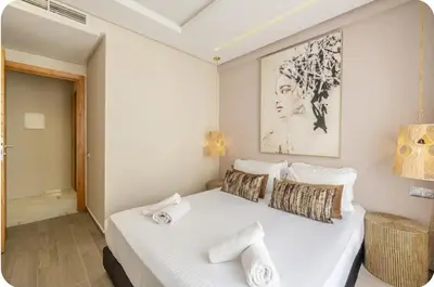 a bedroom with a white bed with a picture on the wall at Appartement en hyper Centre in Marrakech