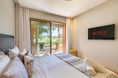 a bedroom with a bed with a tv on the wall at Elevated Elegance A Stylish Golf Atlas Apartment in Marrakech