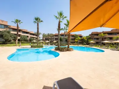 a large swimming pool with palm trees in a resort at Elevated Elegance A Stylish Golf Atlas Apartment in Marrakech