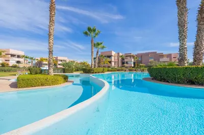 a swimming pool at a resort with palm trees at Elevated Elegance A Stylish Golf Atlas Apartment in Marrakech